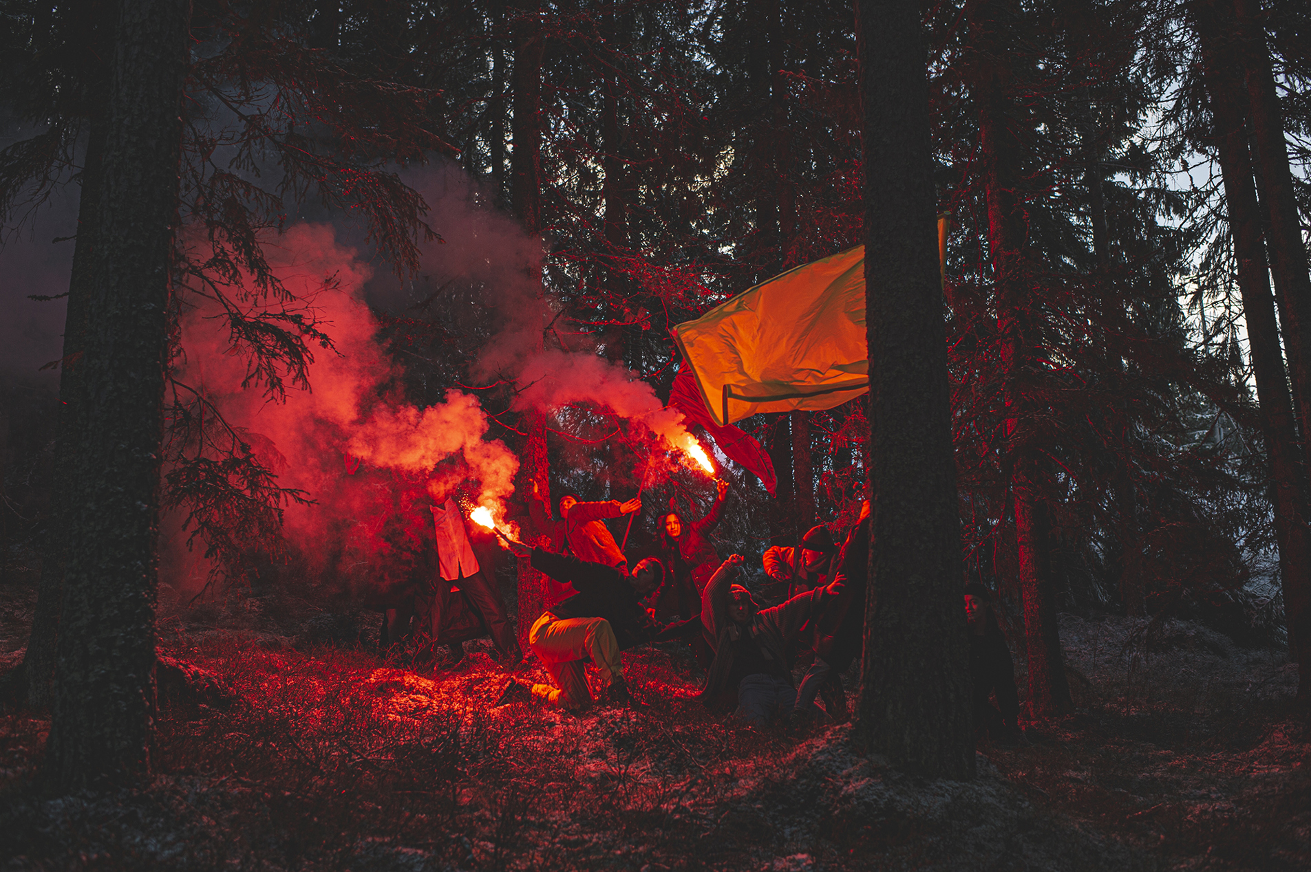 Dansare från det samtida danskompaniet Norrdans dansar i en skog med rök och signalljus.