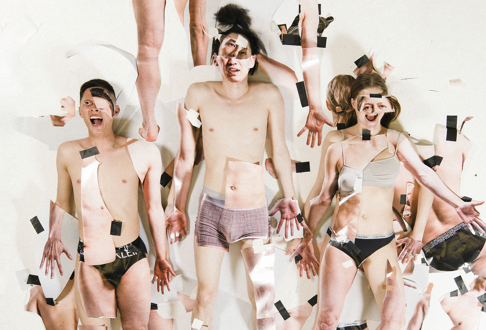 Dancers from the contemporary dance company Norrdans are lying on the floor with cut-outs of body parts and faces taped to themselves.